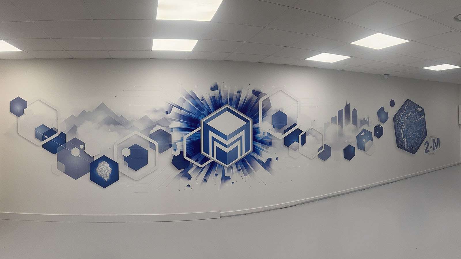 Fresque murale panoramique bleue avec le logo 2-M, imprimée sur un mur blanc des bureaux de l'entreprise